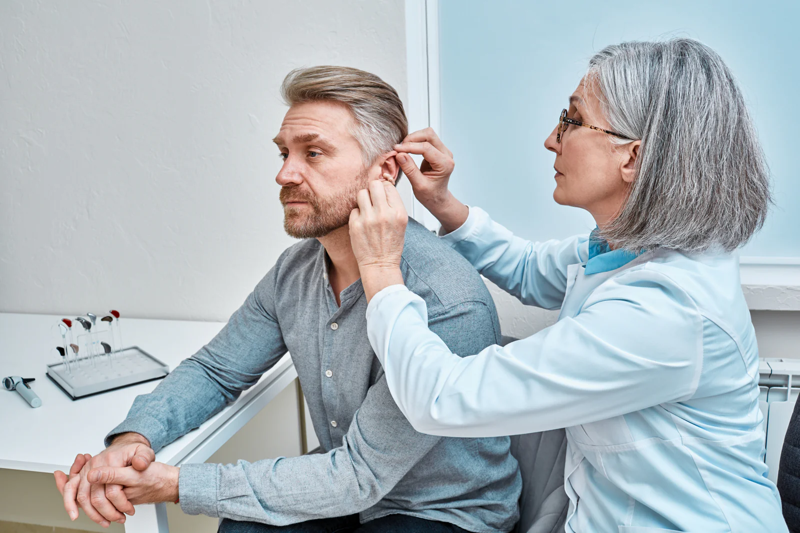 Healthcare professional examining a man's ears, part of the hearing services program Australia.